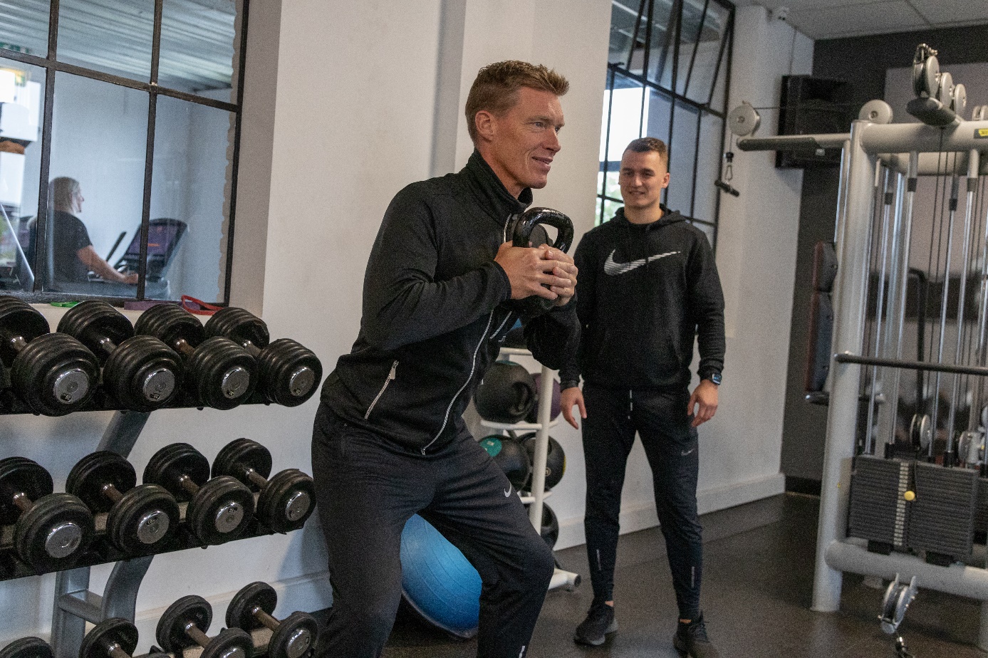 Niek Timmer begeleidt een klant tijdens een kettlebell-oefening in de sportschool